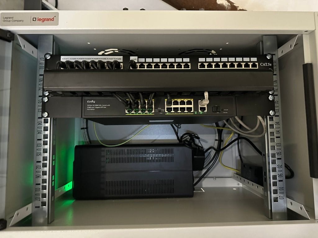 Datový rack kamerového systému s patch panelem popsaným podle kamer, PoE switchem a záložním zdrojem